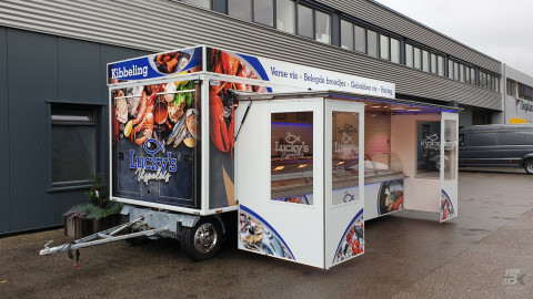 Zijaanzicht van een verkoopwagen voor vis met geopende luifel en zijborden