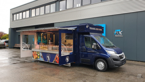 Zijaanzicht van een verkoopwagen voor vis met geopende luifel en zijborden