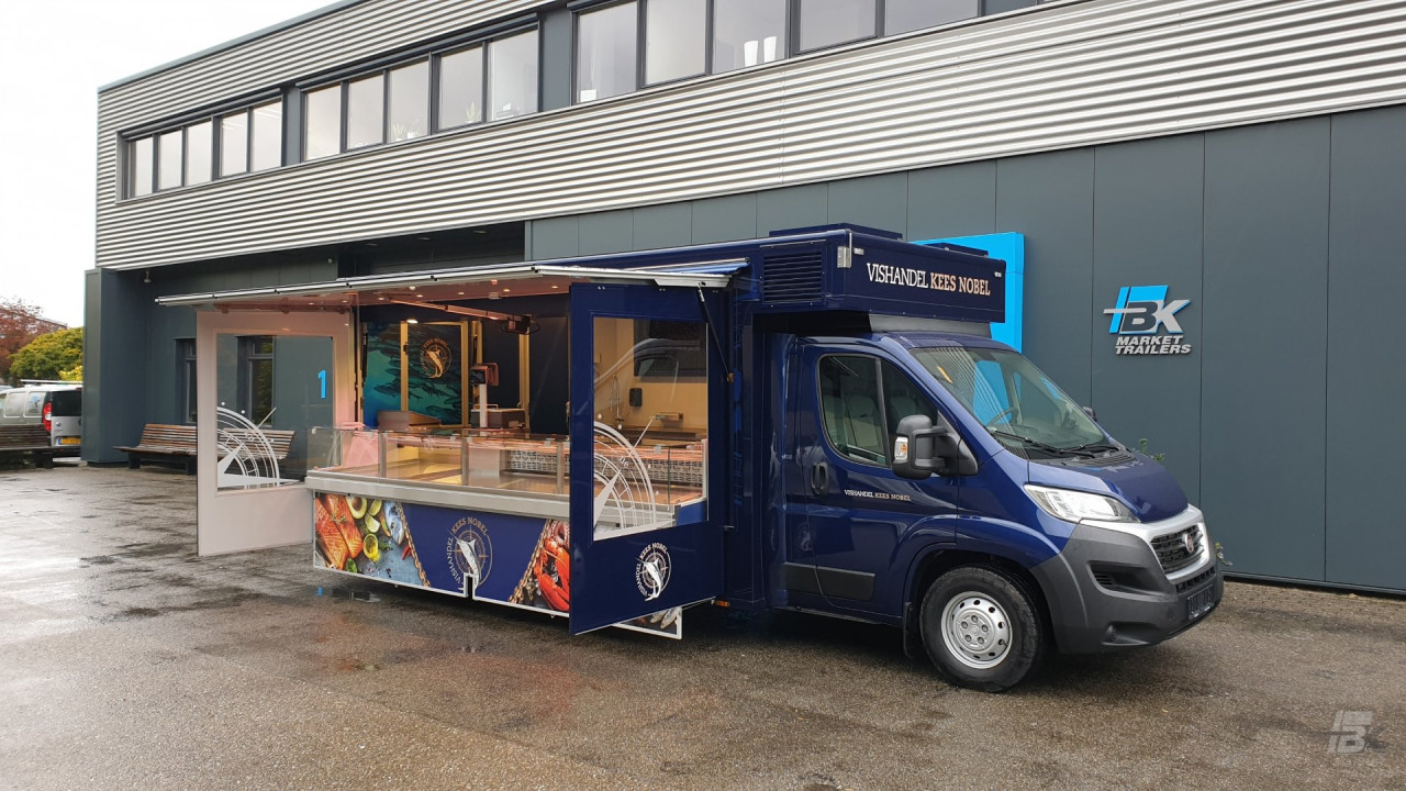 Zijaanzicht van een verkoopwagen voor vis met geopende luifel en zijborden