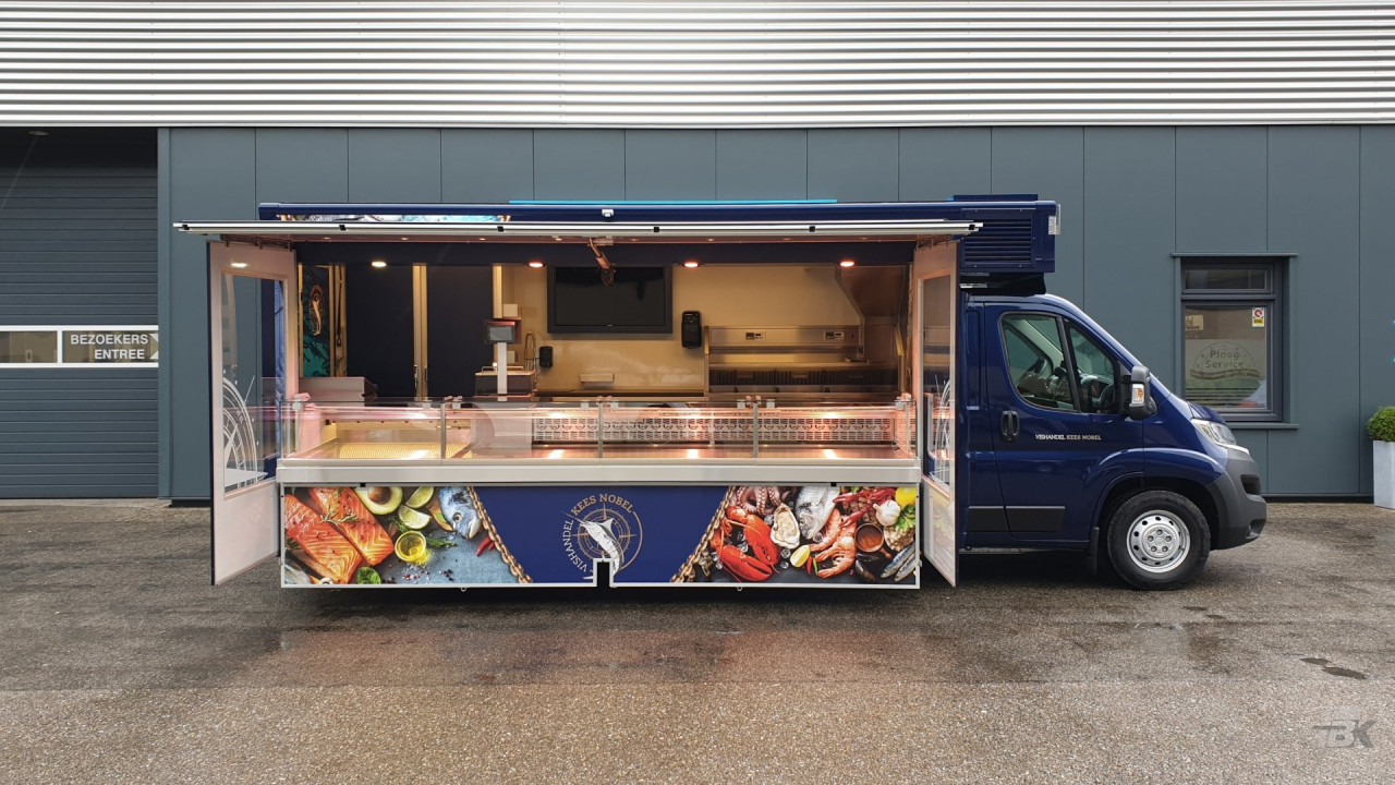 Zijaanzicht van een verkoopwagen voor vis met geopende luifel en zijborden