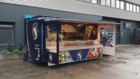Zijaanzicht van een verkoopwagen voor vis met geopende luifel en zijborden