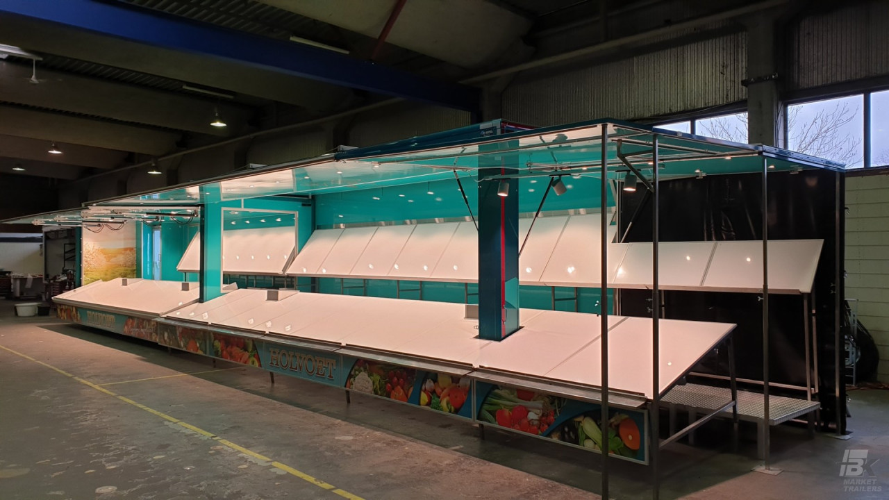 Zijaanzicht van een uitschuifbare aanhangwagen voor groente en fruit met geopende luifel