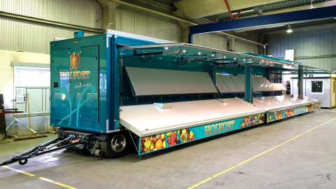 Zijaanzicht van een uitschuifbare aanhangwagen voor groente en fruit met geopende luifel