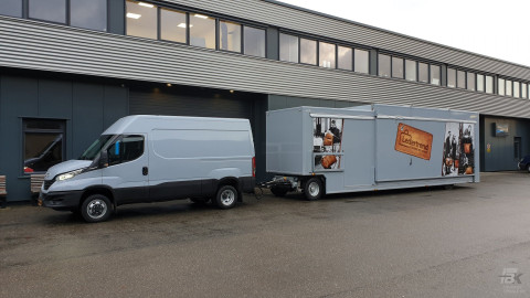 Zijaanzicht van een bus met aanhangwagen voor lederwaren