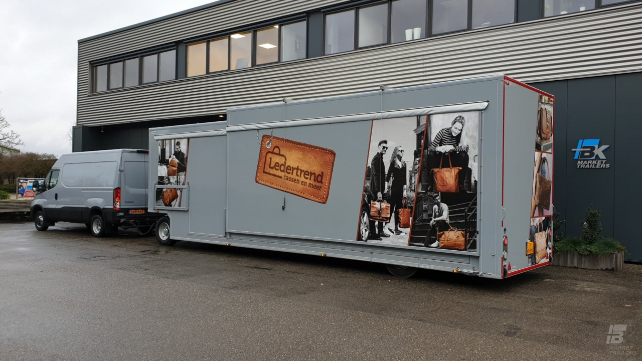 Zijaanzicht van een bus met aanhangwagen voor lederwaren