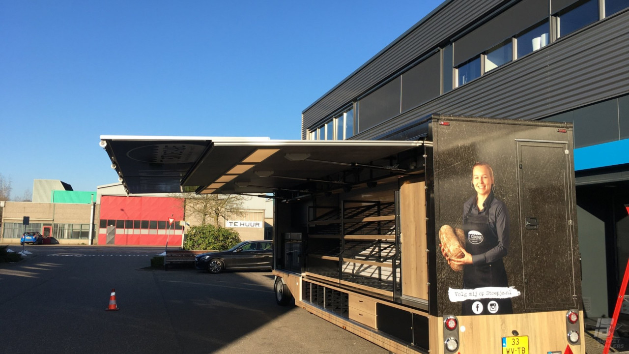Achteraanzicht van een smalle aanhangwagen voor brood en banket met geopende luifel