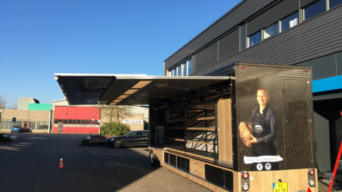 Achteraanzicht van een smalle aanhangwagen voor brood en banket met geopende luifel