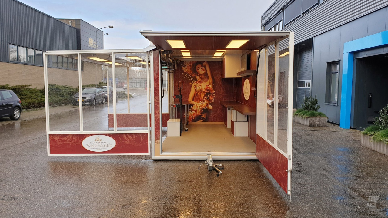 Vooraanzicht van een aanhangwagen voor bloemen met geopende luifel en zijborden