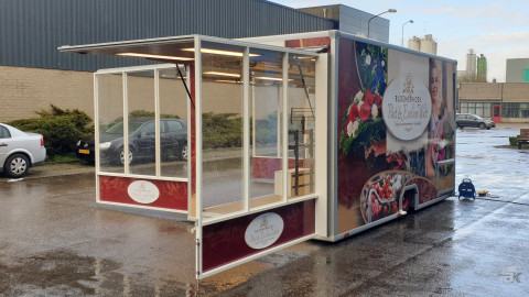 Zijaanzicht van een aanhangwagen voor bloemen met geopende luifel en zijborden