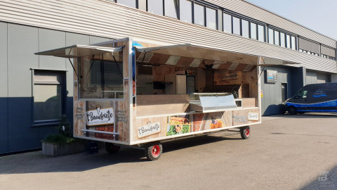 Zijaanzicht van een aanhangwagen voor patat en snacks met geopende luifel