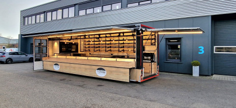 Zijaanzicht van een aanhangwagen voor brood en banket met geopende luifel en zijbord