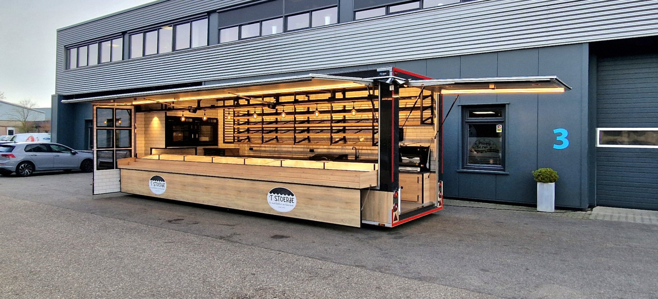 Zijaanzicht van een aanhangwagen voor brood en banket met geopende luifel en zijbord