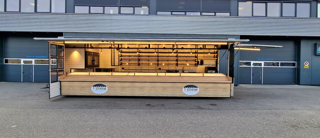 Zijaanzicht van een aanhangwagen voor brood en banket met geopende luifel en zijbord