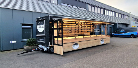Zijaanzicht van een aanhangwagen voor brood en banket met geopende luifel en zijbord