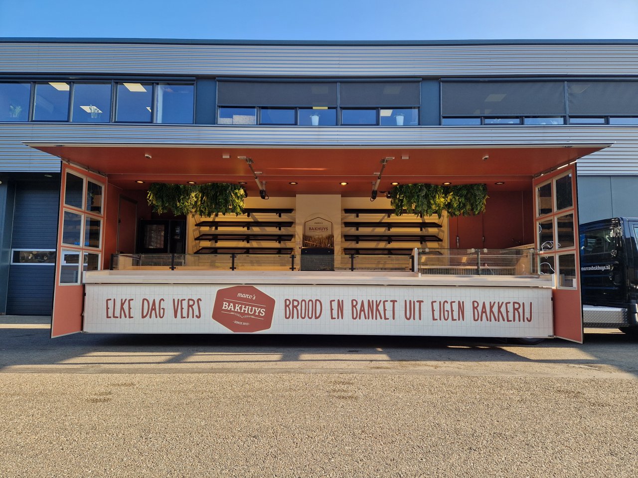 Zijaanzicht van een verkoopwagen oplegger voor brood en banket met geopende luifel