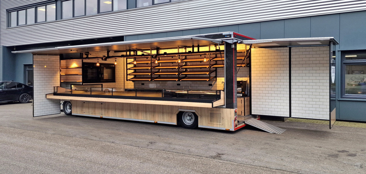 Zijaanzicht van een aanhangwagen voor brood en banket met geopende luifel en zijbord