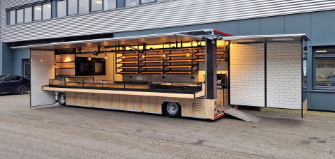 Zijaanzicht van een aanhangwagen voor brood en banket met geopende luifel en zijbord