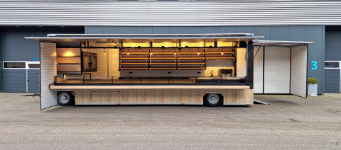 Zijaanzicht van een aanhangwagen voor brood en banket met geopende luifel en zijbord