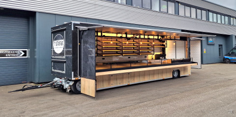 Zijaanzicht van een aanhangwagen voor brood en banket met geopende luifel en zijbord