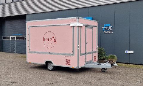 Zijaanzicht van een aanhangwagen voor koekjes, koffie en ijs met gesloten luifel