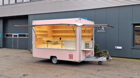 Zijaanzicht van een aanhangwagen voor koekjes, koffie en ijs met geopende luifel