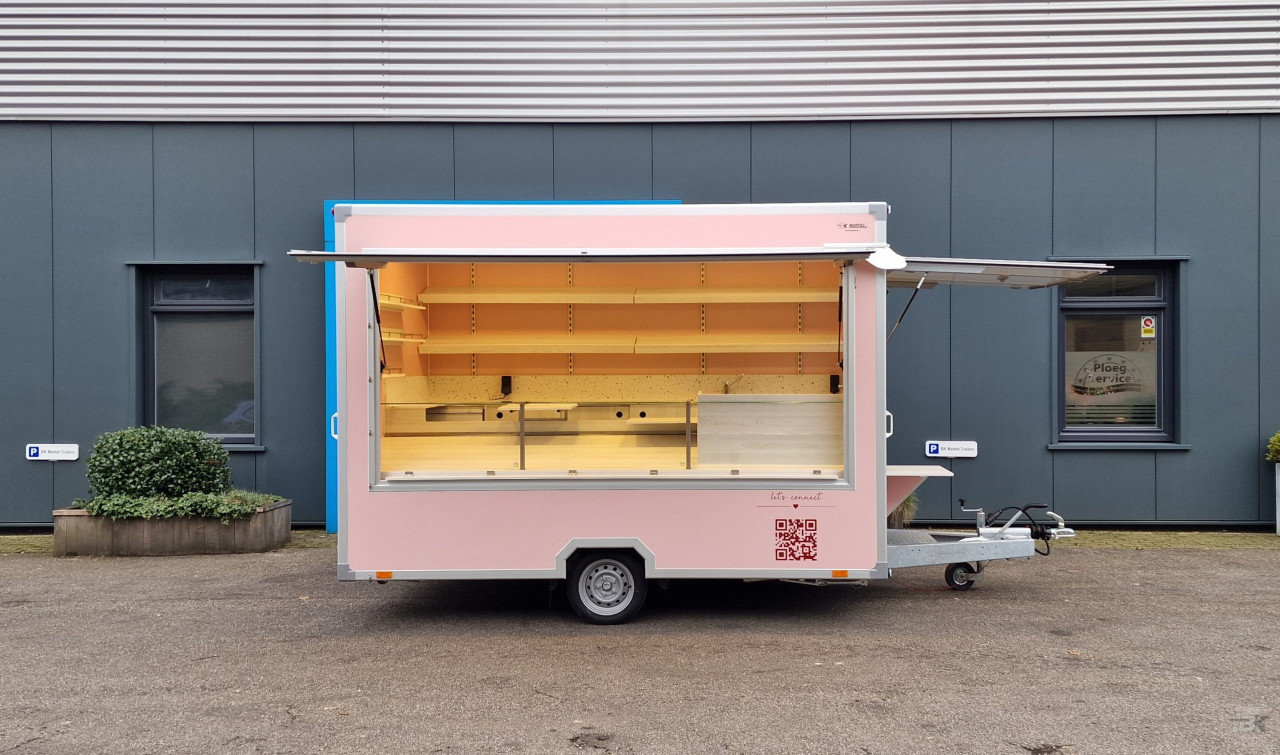 Zijaanzicht van een aanhangwagen voor koekjes, koffie en ijs met geopende luifel