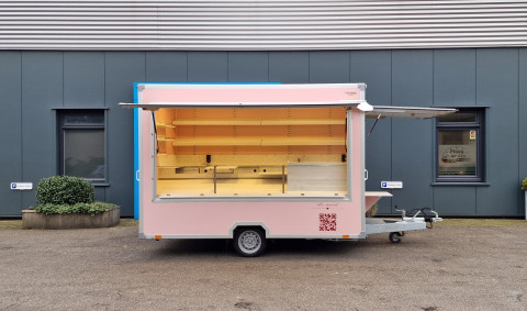 Zijaanzicht van een aanhangwagen voor koekjes, koffie en ijs met geopende luifel