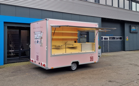 Zijaanzicht van een aanhangwagen voor koekjes, koffie en ijs met geopende luifel