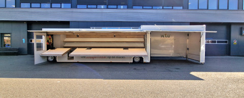 Zijaanzicht van een aanhangwagen voor groente en fruit met geopende luifel en zijbord
