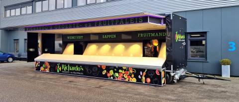 Zijaanzicht van een aanhangwagen voor groente en fruit met geopende luifel