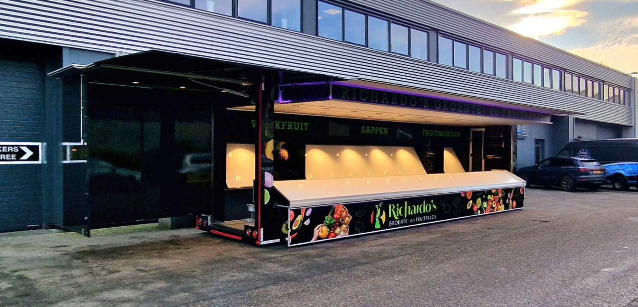 Zijaanzicht van een aanhangwagen voor groente en fruit met geopende luifel