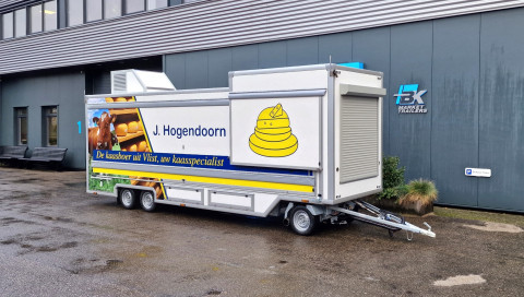 Zijaanzicht van een smalle aanhangwagen voor kaas met gesloten luifel