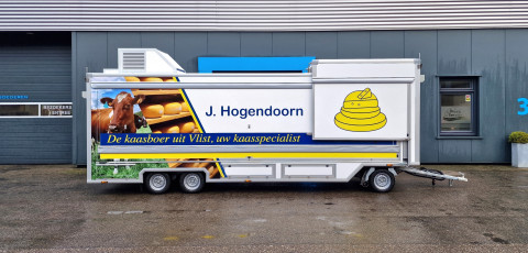 Zijaanzicht van een smalle aanhangwagen voor kaas met gesloten luifel