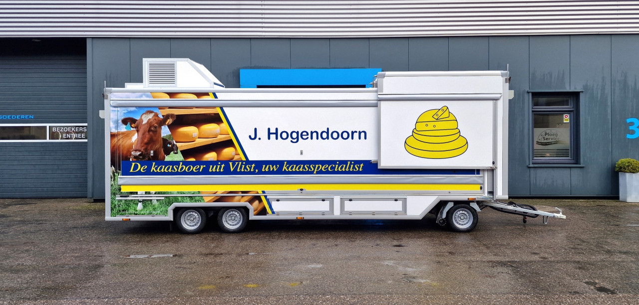 Zijaanzicht van een smalle aanhangwagen voor kaas met gesloten luifel