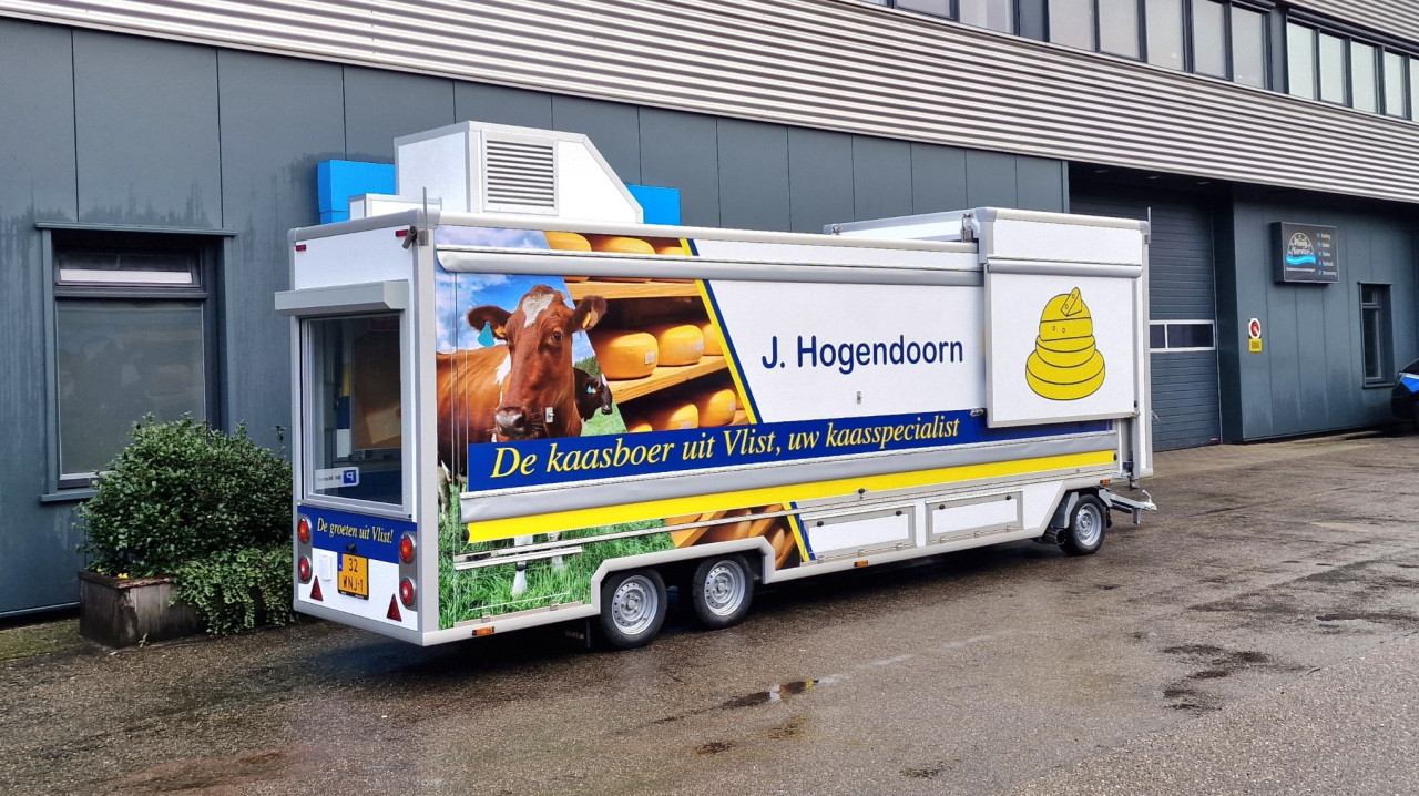 Zijaanzicht van een smalle aanhangwagen voor kaas met gesloten luifel