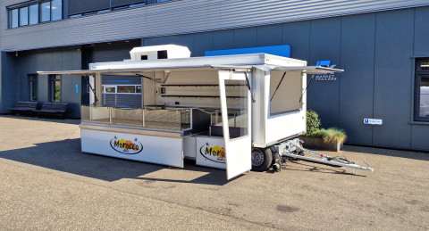 Zijaanzicht van een aanhangwagen voor noten met geopende luifel en zijbord