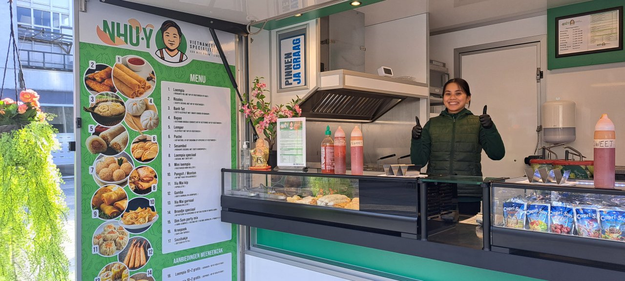 Lachende eigenaresse in haar verkoopwagen voor Vietnamese specialiteiten